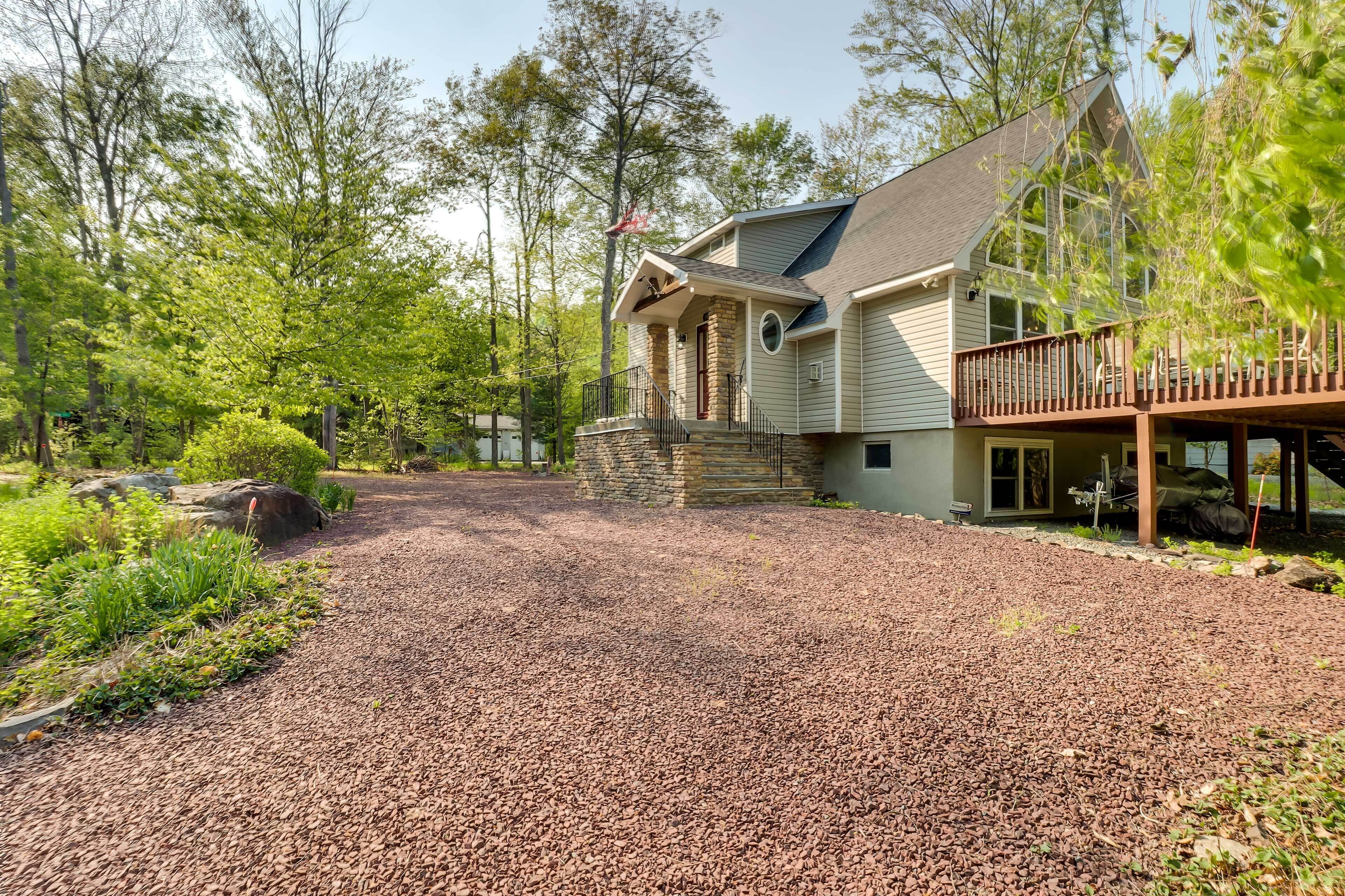 A two-story house with a stone foundation, a covered porch, and a gravel driveway.