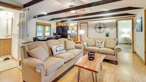 Un salon spacieux avec deux canapés beige, une table basse en bois et une cuisine en arrière-plan.