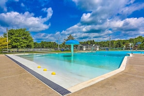 A swimming pool with a blue roof structure, surrounded by a concrete deck and a metal fence.