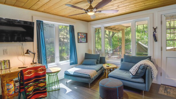 A modern living room with a sofa, a small table, and a TV mounted on the wall. - Strawberry Cabin Rental w/ Deck & Mountain Views! (Pine)