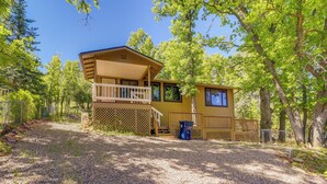 A two-story cabin with a balcony, surrounded by trees and a gravel driveway. - Strawberry Cabin Rental w/ Deck & Mountain Views! (Pine)