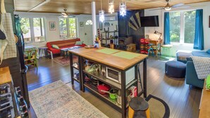 A cozy cabin interior with a wooden ceiling, a central table with a green mat, a sofa, a TV, and a fireplace. - Strawberry Cabin Rental w/ Deck & Mountain Views! (Pine)