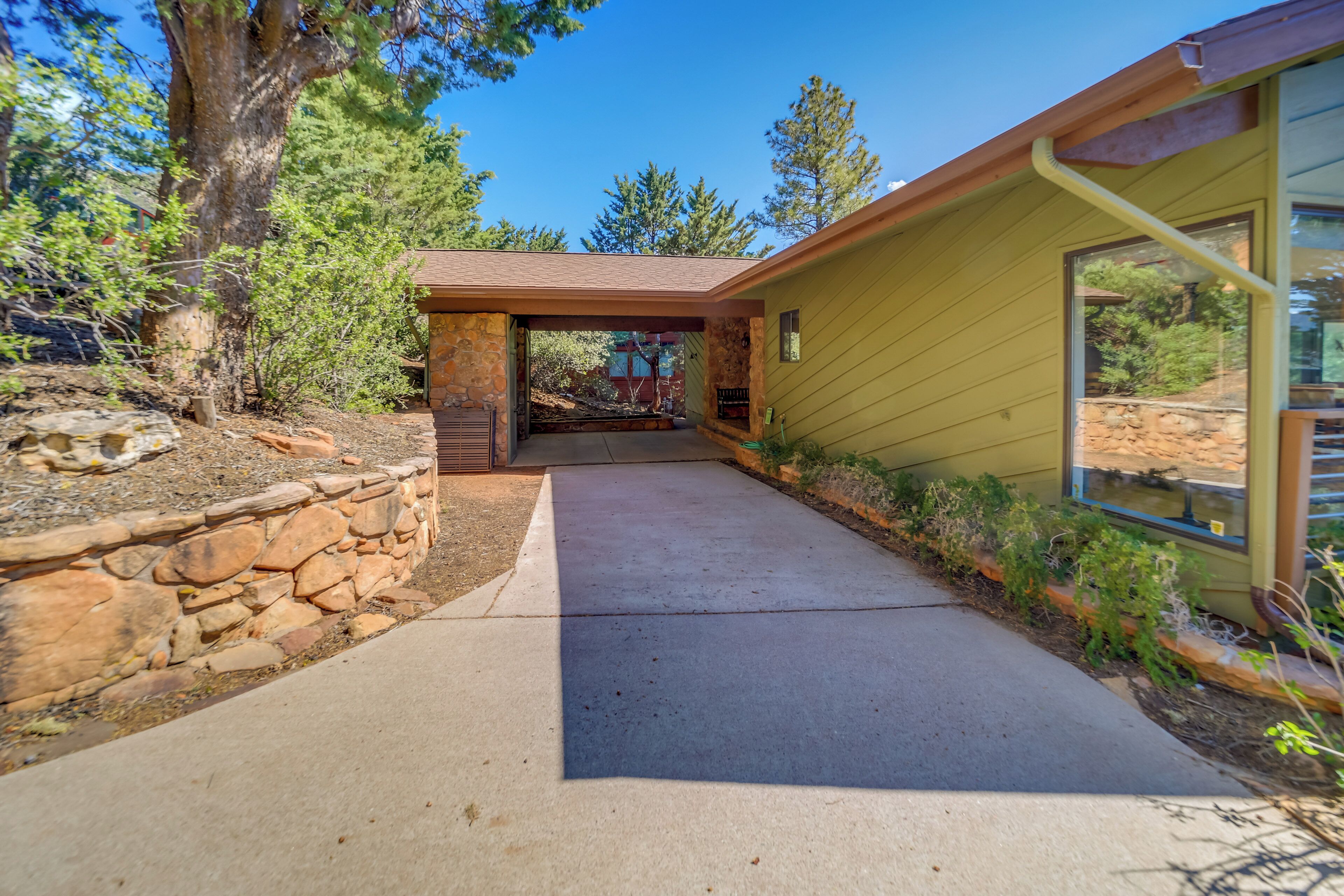 A house with a stone retaining wall, a concrete driveway, and a covered entryway.