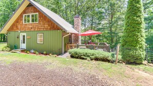 A rustic cabin with a stone chimney, a wooden deck, and a red umbrella. - Pet-friendly Murphy Home: Grilling Deck + Fire Pit (Murphy)