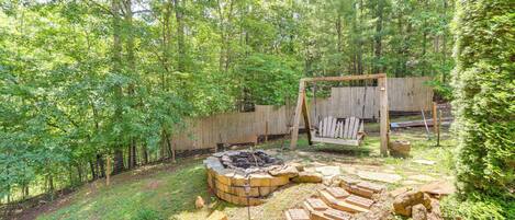 A backyard with a fire pit, wooden deck, and a fenced area.