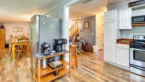 A kitchen with white cabinets, a stainless steel refrigerator, a coffee maker, and a wooden dining table with chairs. - Pet-friendly Murphy Home: Grilling Deck + Fire Pit (Murphy)