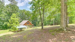 A cabin with a covered patio, surrounded by a forested area. - Pet-friendly Murphy Home: Grilling Deck + Fire Pit (Murphy)