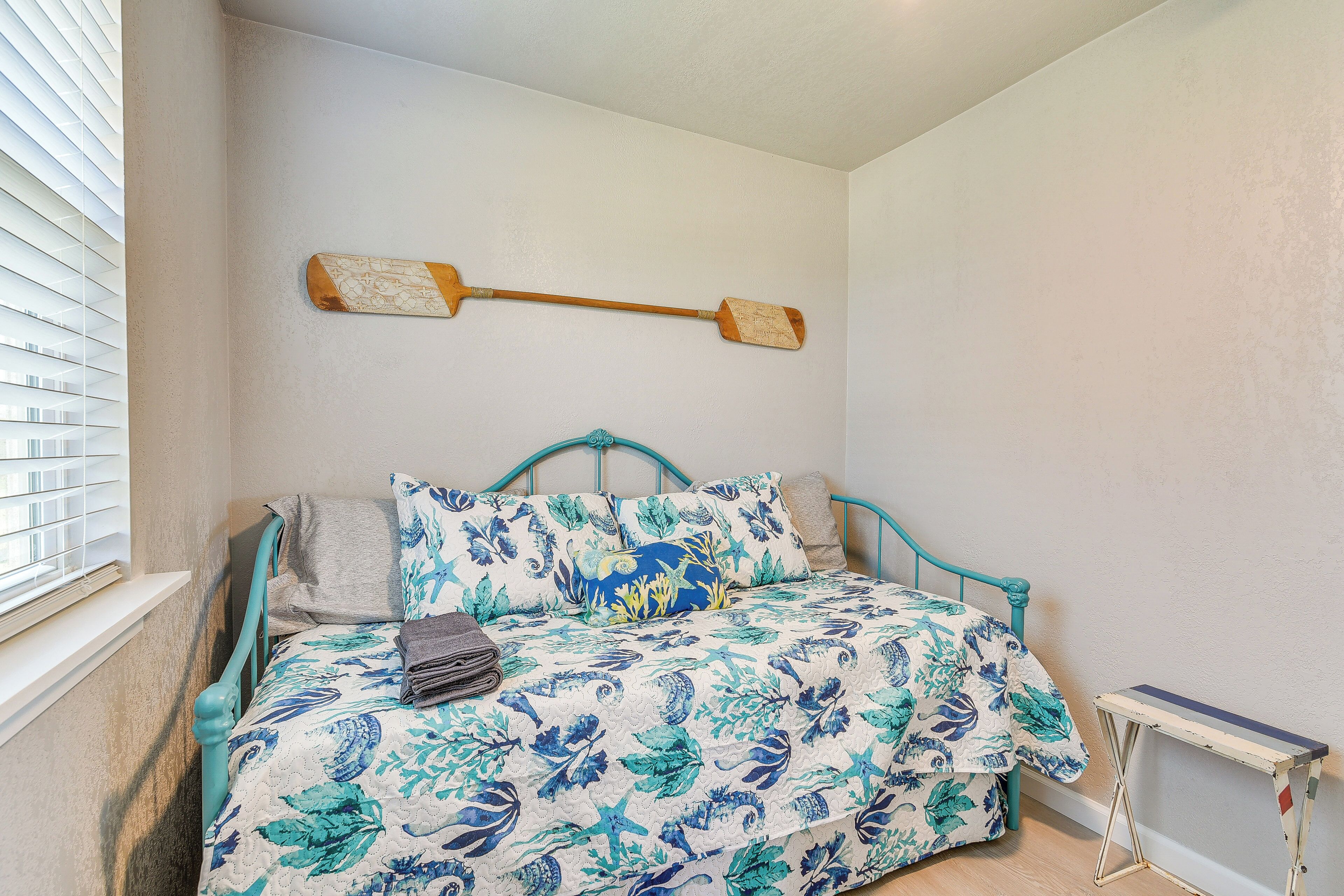 A bedroom with a bed, a window with blinds, and a wall-mounted wooden object.