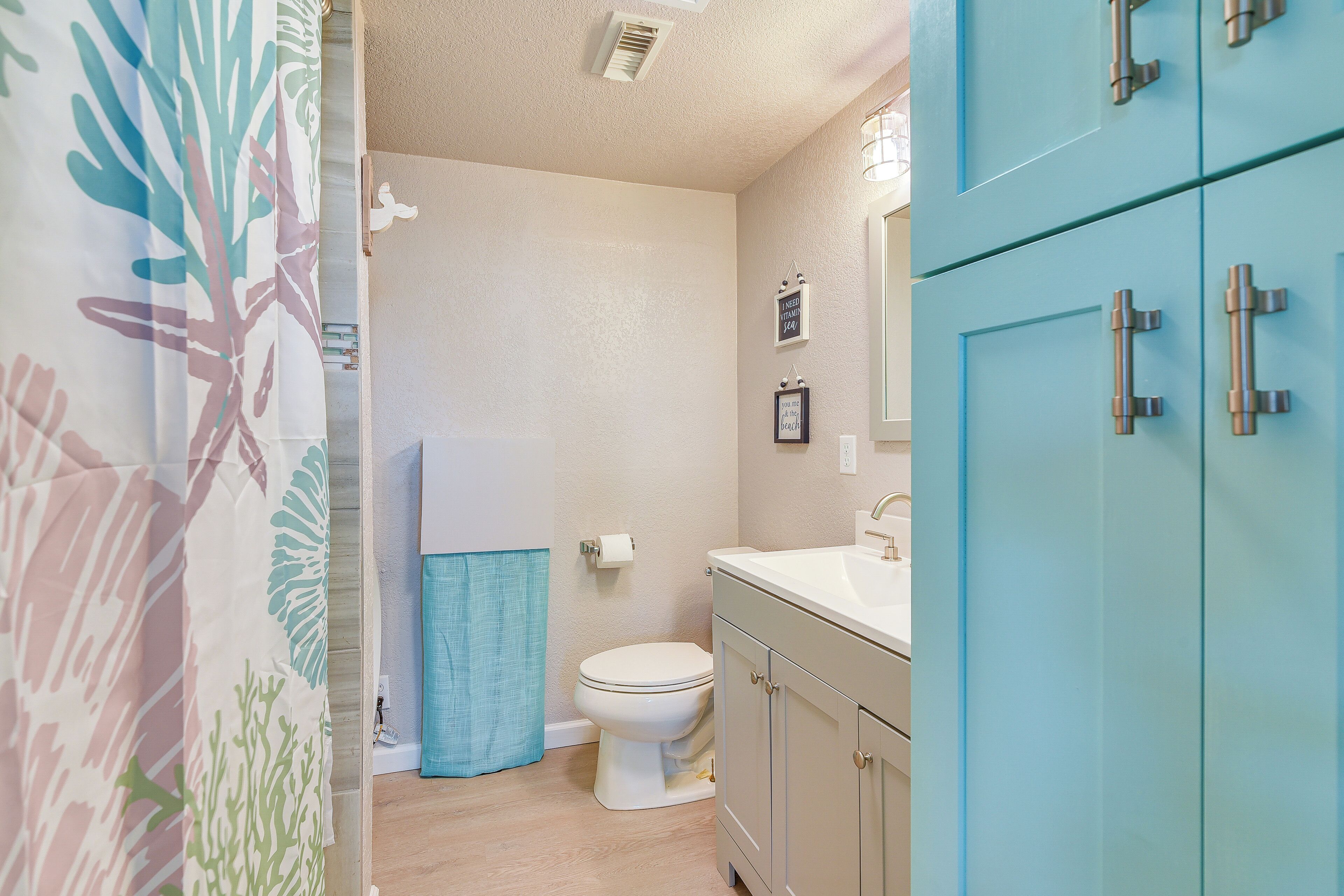 A bathroom with a toilet, sink, and cabinets.