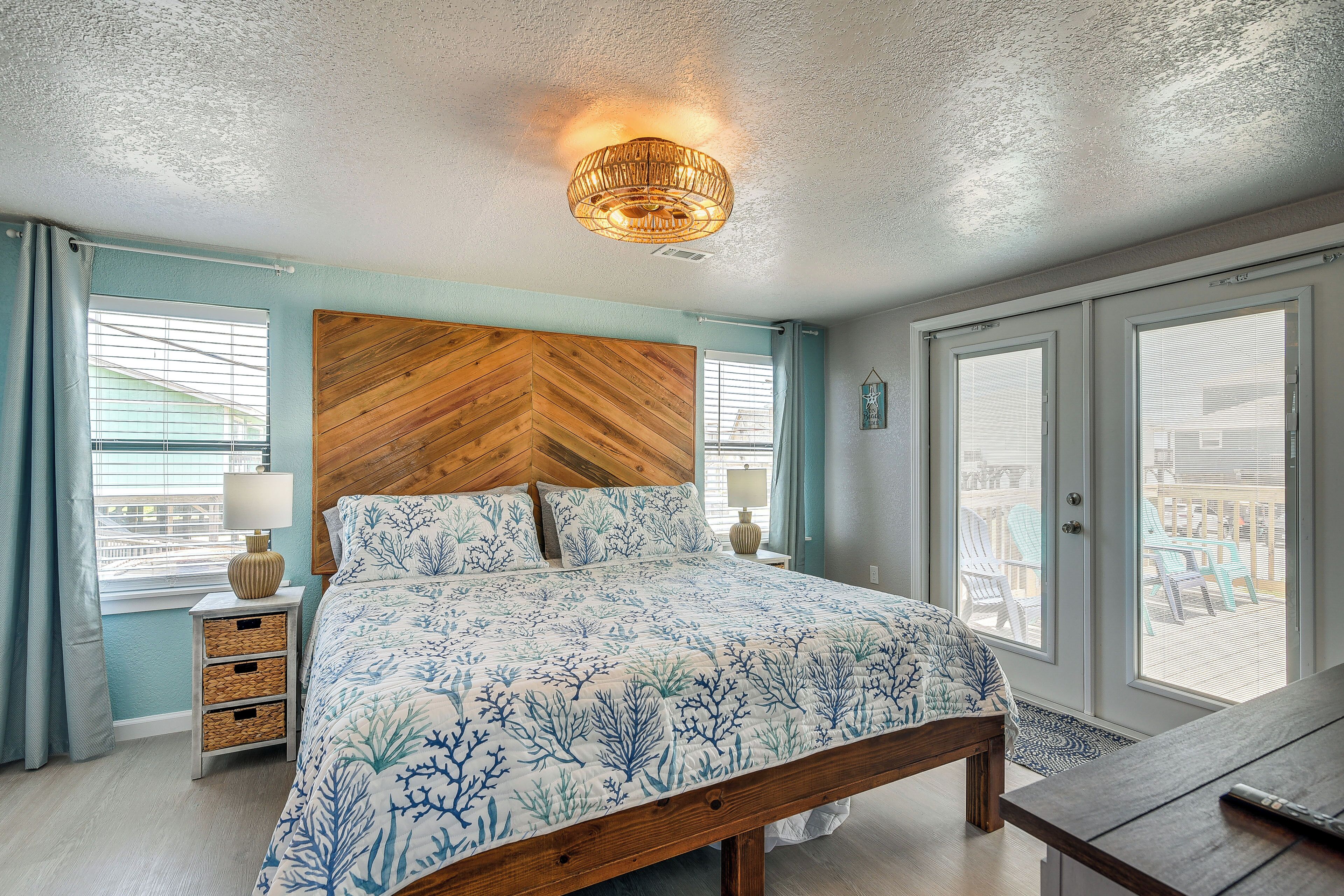 A bedroom with a large bed, wooden headboard, two bedside tables with lamps, and a view through the door.