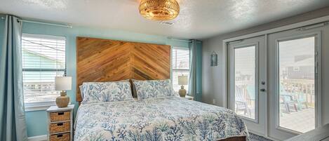 A bedroom with a large bed, wooden headboard, two bedside tables with lamps, and a view through the door.