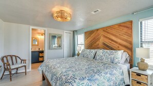 Una camera da letto con un letto, una testiera in legno, un comodino, una sedia e una lampada a soffitto.
