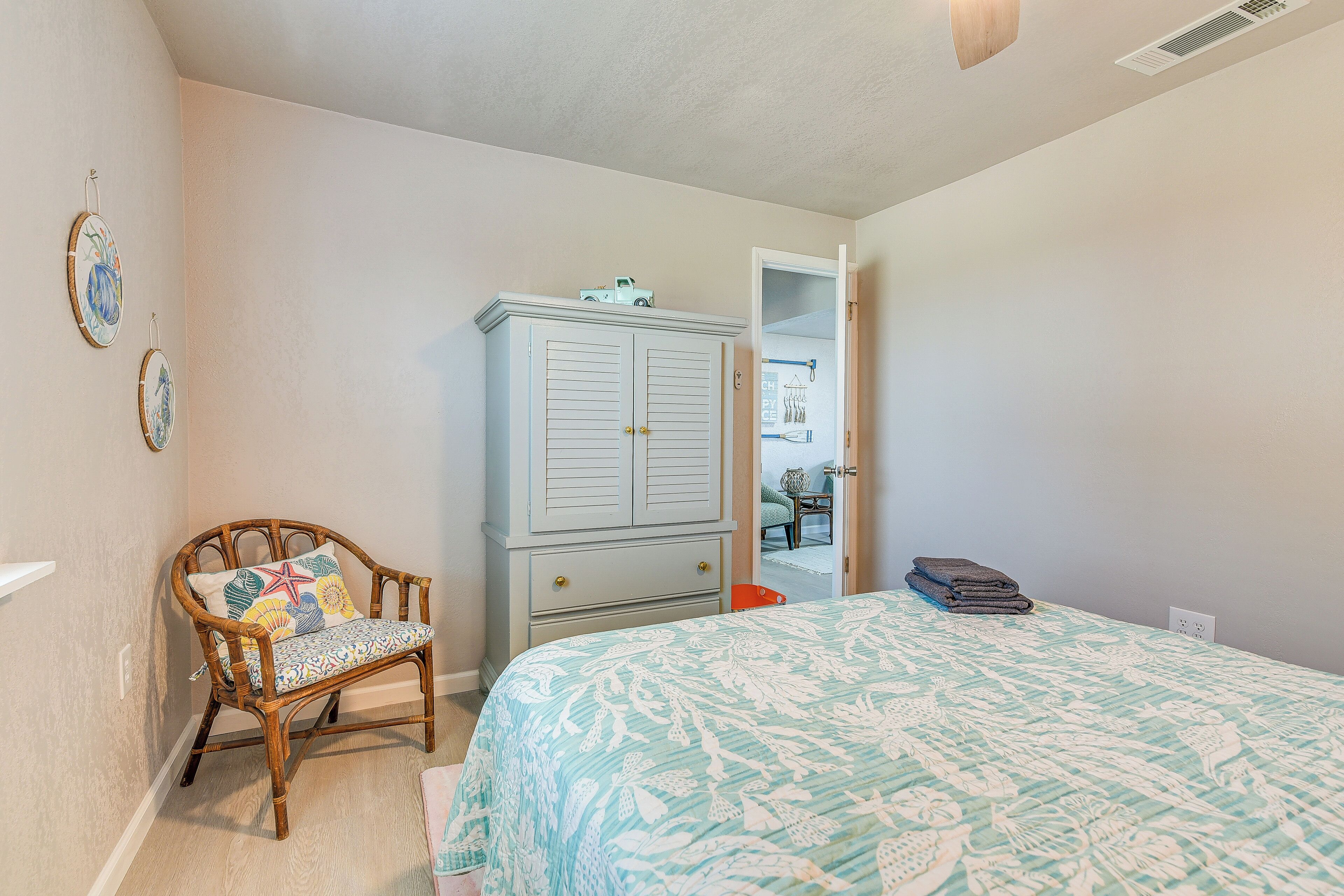 A bedroom with a bed, a wooden chair, a wardrobe, and a door leading to another room.