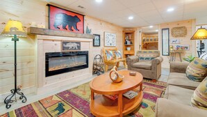 A cozy living room with a fireplace, wooden walls, a sofa, and a coffee table. - Secluded Murphy Vacation Rental w/ Private Hot Tub (Murphy)