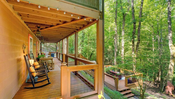 A wooden deck with rocking chairs, a staircase, and a view of the forest. - Secluded Murphy Vacation Rental w/ Private Hot Tub (Murphy)