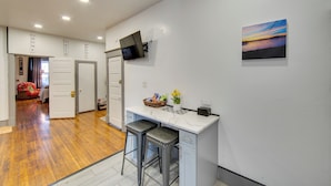 A kitchen with a marble countertop, two bar stools, a television mounted on the wall, and a painting above the counter. - < 2 Mi to Downtown & Capitol: Harrisburg Hideaway (Harrisburg)