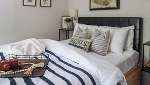 A neatly made bed with striped bedding, a framed map of Paris, and a small plant on a bedside table. - Huguenot Retreat w/ Screened Porch & Lake Access! (Huguenot)
