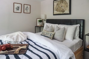 A neatly made bed with striped bedding, a decorative pillow, and a tray with a camera and beads. - Huguenot Retreat w/ Screened Porch & Lake Access! (Huguenot)