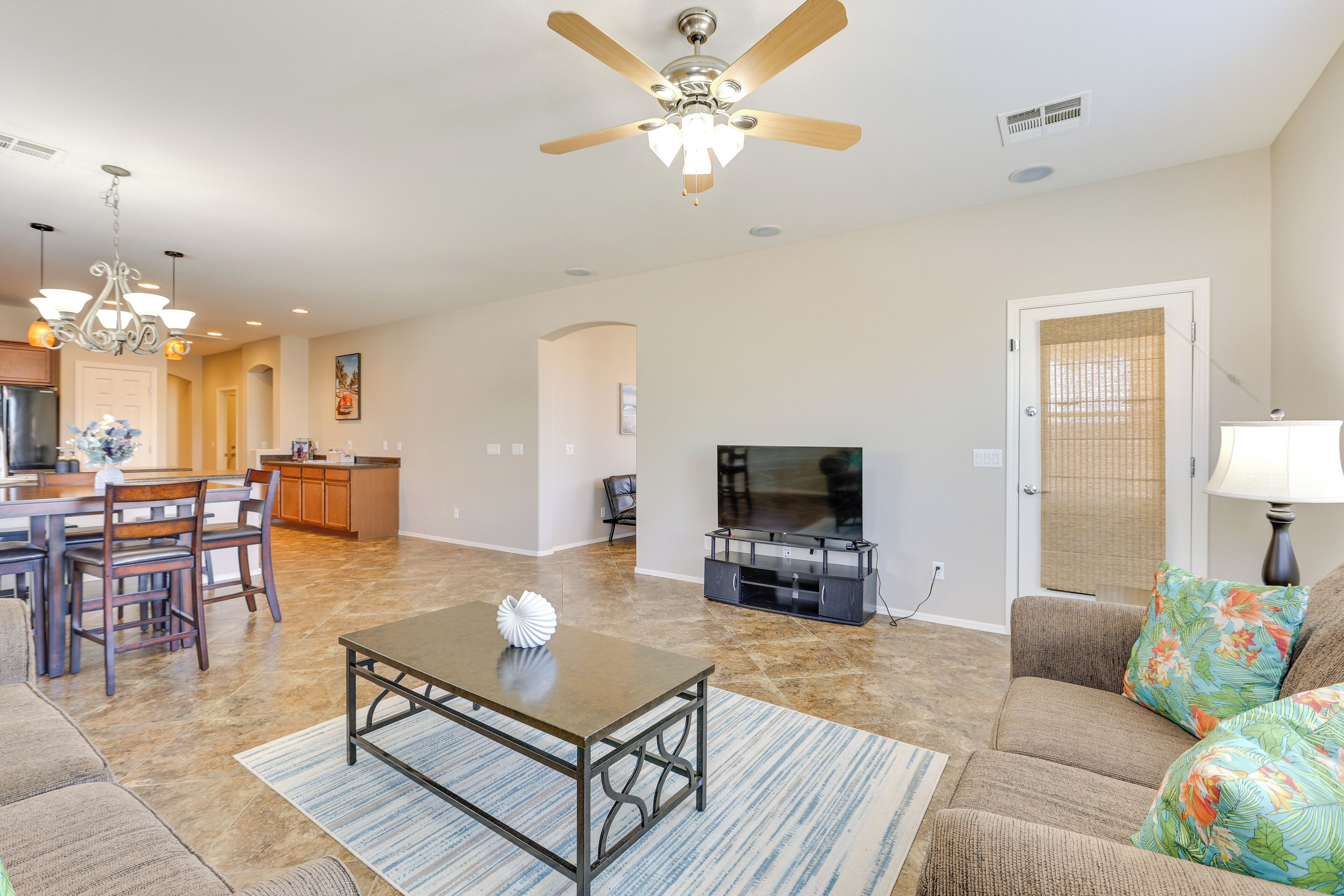 A spacious living room with a dining area, a kitchen, and a television.