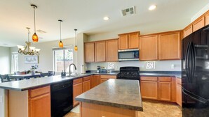 A modern kitchen with wooden cabinets, a large island, stainless steel appliances, and pendant lighting. - Near Parks & Golf: Maricopa Home w/ Covered Patio! (Maricopa)