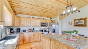 A spacious kitchen with wooden cabinets, granite countertops, a microwave, and a refrigerator. - North Carolina Cabin - Pool Table & Mountain Views (Murphy)
