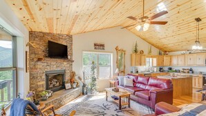 A cozy living room with a fireplace, a red leather couch, and a stone wall. - North Carolina Cabin - Pool Table & Mountain Views (Murphy)