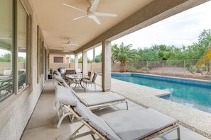 Relax by the pool surrounded by lush vegetation and enjoy a meal or socialize at the adjacent table.