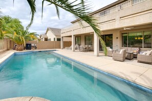 Relax by the pool surrounded by lush greenery and outdoor furniture.