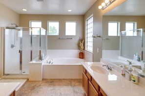 Bathroom features a bathtub, glass-enclosed shower, and wooden cabinets.