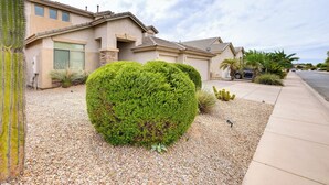 A residential house with a well-maintained front yard, including a large green bush and a cactus. - Maricopa Oasis w/ Game Room + Community Perks! (Maricopa)