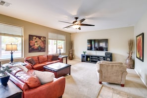Relax in a stylish living room with a ceiling fan, flat-screen TV, and comfortable seating area.