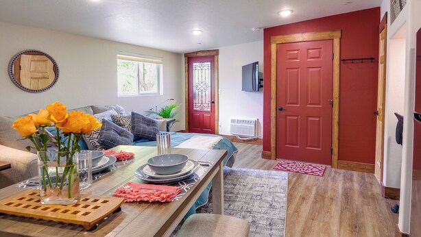 A dining area with a wooden table set for four, a vase with yellow flowers, and a red door in the background. - Southern Colorado Rental: 10 Mi to Mesa Verde (Cortez)