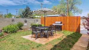 A backyard with a patio table and chairs, a grill, and a wooden fence. - Southern Colorado Rental: 10 Mi to Mesa Verde (Cortez)