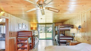 A cabin with a bunk bed, a single bed, a bookshelf, a lamp, and a ceiling fan. - Lakefront Minnesota Escape w/ Fire Pit & Boat Dock (Emily)