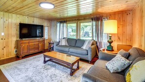 A wooden-paneled living room with a television, sofa, coffee table, and lamp. - Lakefront Minnesota Escape w/ Fire Pit & Boat Dock (Emily)