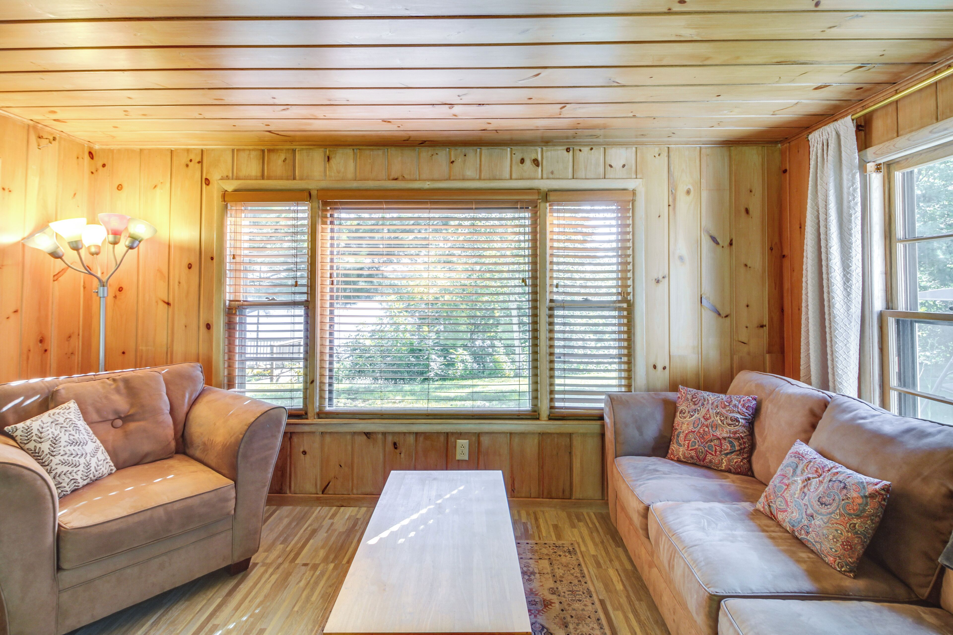 A wooden-paneled room with two leather sofas, a coffee table, and a floor lamp.