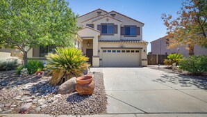 A two-story house with a garage, surrounded by a landscaped garden with rocks, a large pot, and various plants. - Spacious Maricopa Home Rental w/ Pool & Hot Tub! (Maricopa)