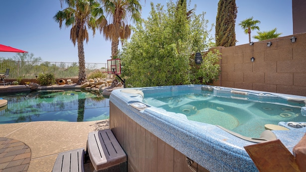 A hot tub with a stone wall and palm trees in the background. - Spacious Maricopa Home Rental w/ Pool & Hot Tub! (Maricopa)