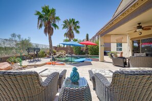A patio area with wicker furniture, a pool, and palm trees. - Spacious Maricopa Home Rental w/ Pool & Hot Tub! (Maricopa)
