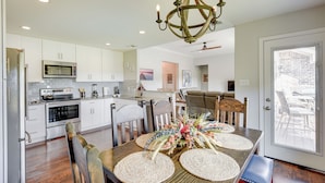 A modern kitchen with white cabinets, stainless steel appliances, and a dining area with a wooden table and chairs. - Inviting Granbury Home w/ Fire Pit: 3 Mi to Lake! (Granbury)