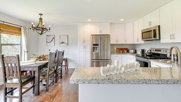 A modern kitchen with white cabinets, a stainless steel refrigerator, a microwave, and a granite countertop. - Inviting Granbury Home w/ Fire Pit: 3 Mi to Lake! (Granbury)