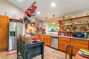 Una cocina moderna con electrodomésticos de acero inoxidable, armarios de madera y una variedad de vajilla y utensilios de colores.