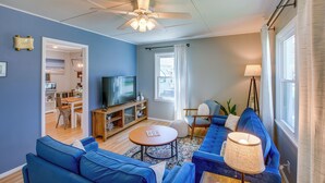 A modern living room with a blue sofa, a wooden coffee table, a ceiling fan, and a television. - Sturgeon Bay Home ~ 6 Mi to Potawatomi State Park (Sturgeon Bay)