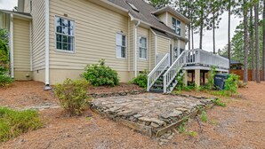 A two-story house with a stone patio, a wooden deck, and a staircase leading to a covered porch. - North Carolina Getaway on Pinehurst Golf Course! (Pinehurst)