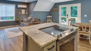 A modern kitchen with a large island, a dining area with chairs, and a cozy seating area with a sofa and pillows. - Dog-friendly Mills River Retreat Near Hiking! (Mills River)