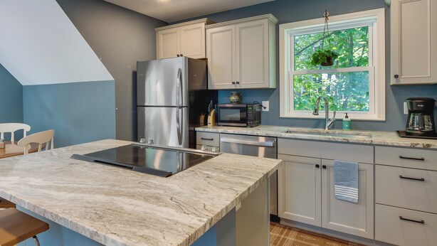 A modern kitchen with a built-in island, stainless steel appliances, and a window with a view of greenery. - Dog-friendly Mills River Retreat Near Hiking! (Mills River)