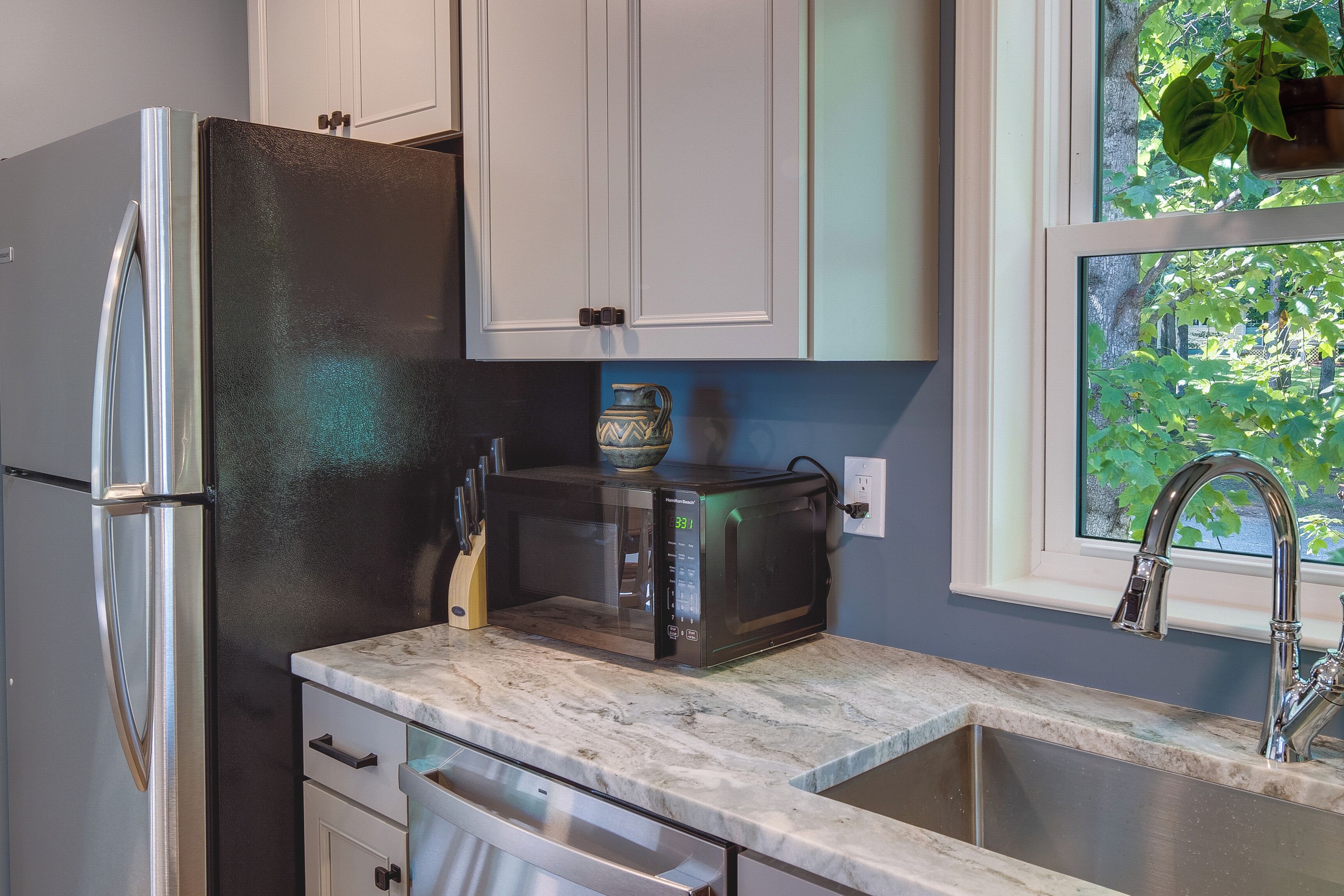 A kitchen with a refrigerator, microwave, and sink.