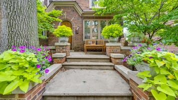 Step up to a traditional home with a welcoming entrance, flanked by lush greenery and vibrant flowers.