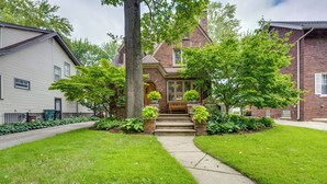 Une maison à deux étages avec un porche à l’avant, une façade en briques et une pelouse bien entretenue.