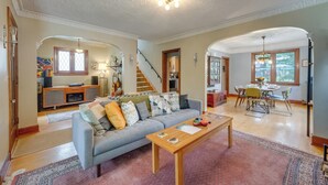 Un salon spacieux avec un canapé gris, une table basse en bois et un coin repas comprenant une table et des chaises.